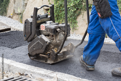Construction Worker With Vibration Plate At Sidewalk Asphalting