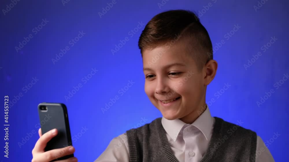 Handsome school boy takes a selfie on his phone. Modern child is photographed on his smartphone. Handsome school boy takes a selfie on his phone. Modern child is photographed on his smartphone.