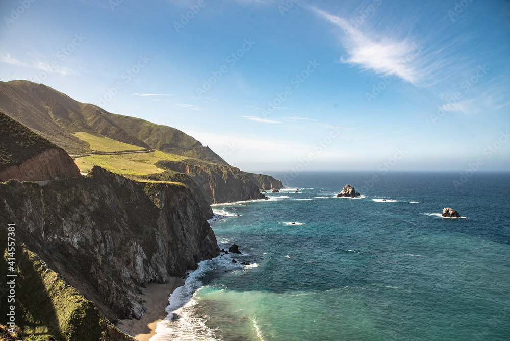 Big Sur during the spring time in California, United States with stunning, pristine, blue, cloudy sky and cliff faces dropping down directly into the Pacific Ocean. 