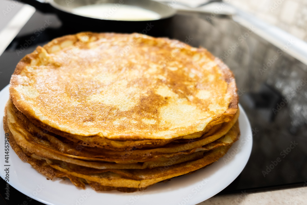 a stack of pancakes on a white plate on a kitchen background a stack of pancakes on a white plate on a kitchen background