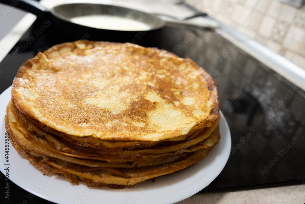 a stack of pancakes on a white plate on a kitchen background a stack of pancakes on a white plate on a kitchen background
