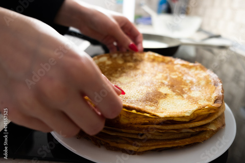 a stack of pancakes on a white plate on a kitchen background