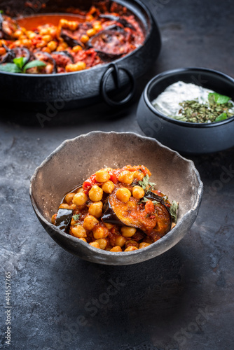 Modern style slow cooked Lebanese vegetarian eggplant stew maghmour served with chickpeas and yoghurt as close-up in a rustic design bowl