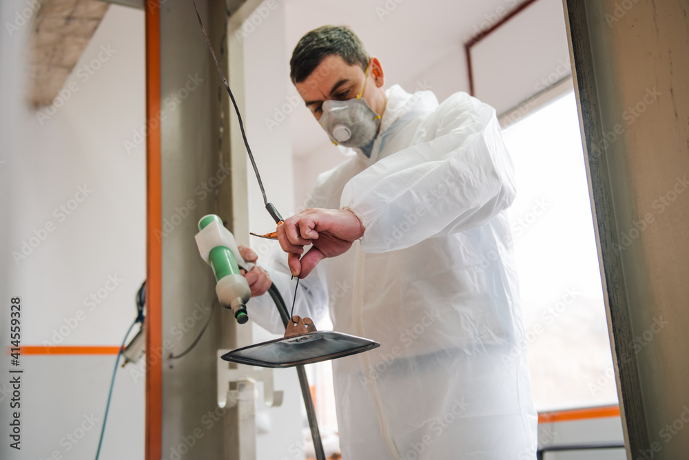 Man painting with spray gun in a workshop