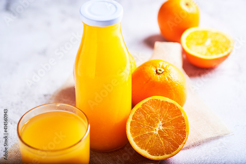  orange juice in a glass container with some oranges