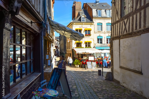 A woman window shops on a sunny day in the Normandy town of Honfleur France with an outdoor sidewalk cafe behind her © Kirk Fisher
