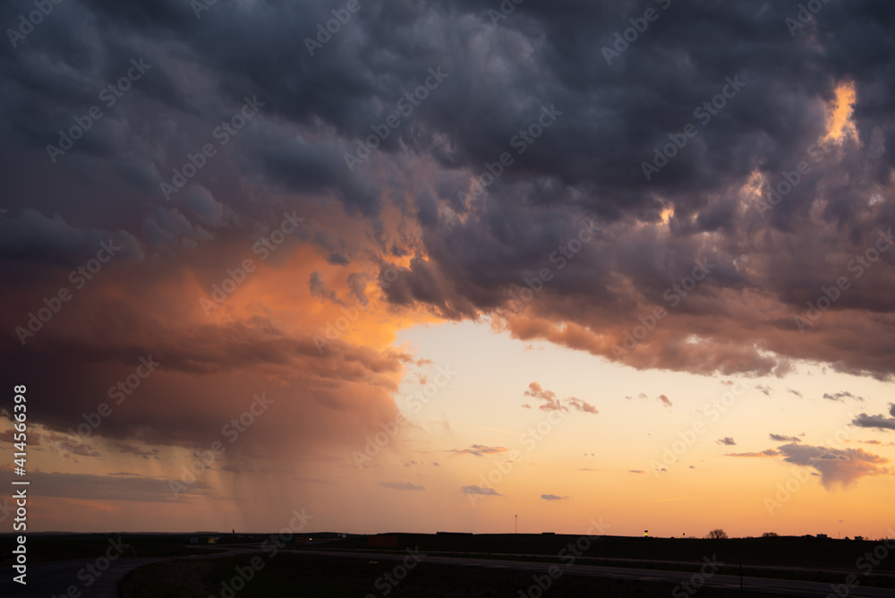 A flat landscape seen before a cloudy storm approaching with pink, orange dark clouds, shining sun and dark country, rural land below. Great for sky replacement for editing photos or drawing. A flat landscape seen before a cloudy storm approaching with pink, orange dark clouds, shining sun and dark country, rural land below. Great for sky replacement for editing photos or drawing.