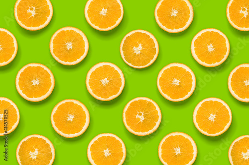 Fruit pattern of orange slices on green background. Flat lay, top view. Food background.