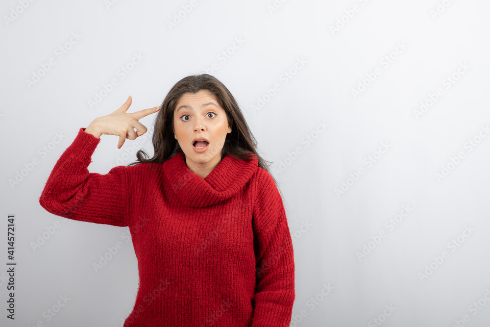 Young woman wearing casual sweater and pointing to head Young woman wearing casual sweater and pointing to head