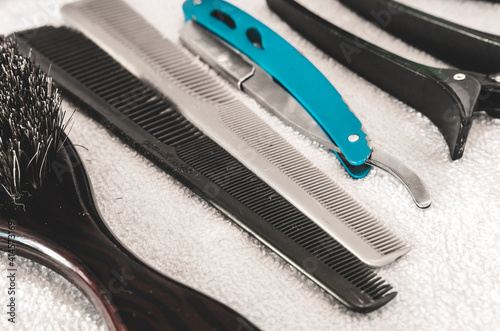 Closeup of a brush, fine combs, a shaving razor and clips on a white towel - tools of a professional barber or hairstylist for men. photo