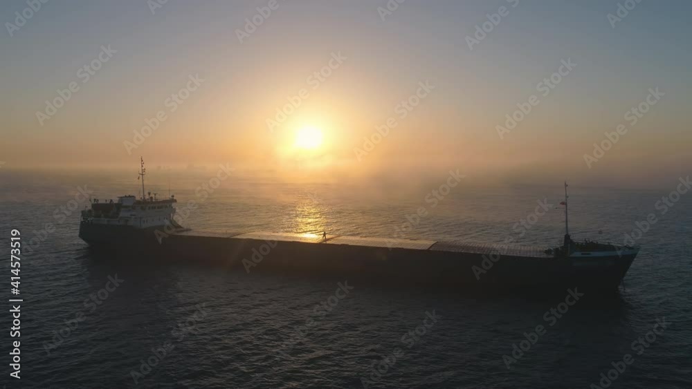Foggy ocean sunrise and sailing cargo ship in open waters, 4K aerial drone video Foggy ocean sunrise and sailing cargo ship in open waters, 4K aerial drone video