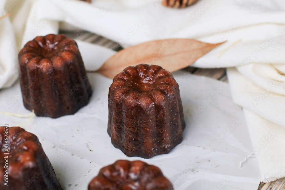 Caneles de bordeaux - traditional French sweet dessert serve with tea or coffee on wooden background. Caneles de bordeaux - traditional French sweet dessert serve with tea or coffee on wooden background.