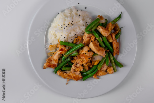 Homemade Stir-fried Chicken with Green String Bean, Onion, Garlic, and Rice. Top View on White Plate and Backgrounds 