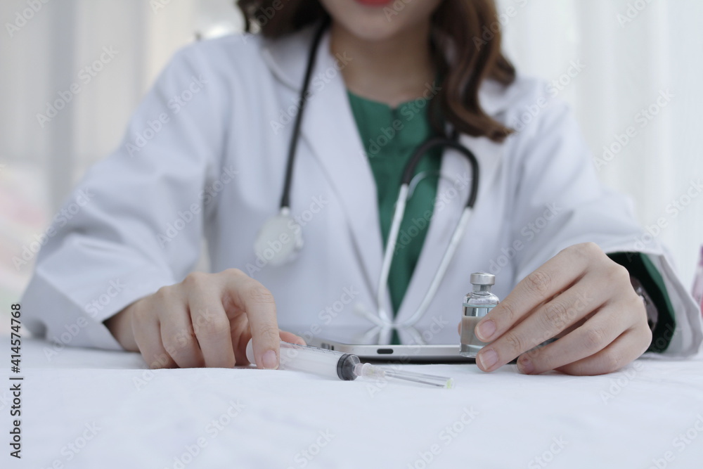 Hand female doctor has vaccine bottle and syringe on the work table,Working doctor,white office of the hospital, healthcare concept Hand female doctor has vaccine bottle and syringe on the work table,Working doctor,white office of the hospital, healthcare concept