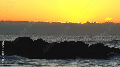 Sunrise over the ocean with silhouette of the rocks