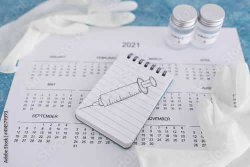 covid-19 vaccine against the pandemic, 2021 calendar with syringe sketch on notepad and disposable gloves on it