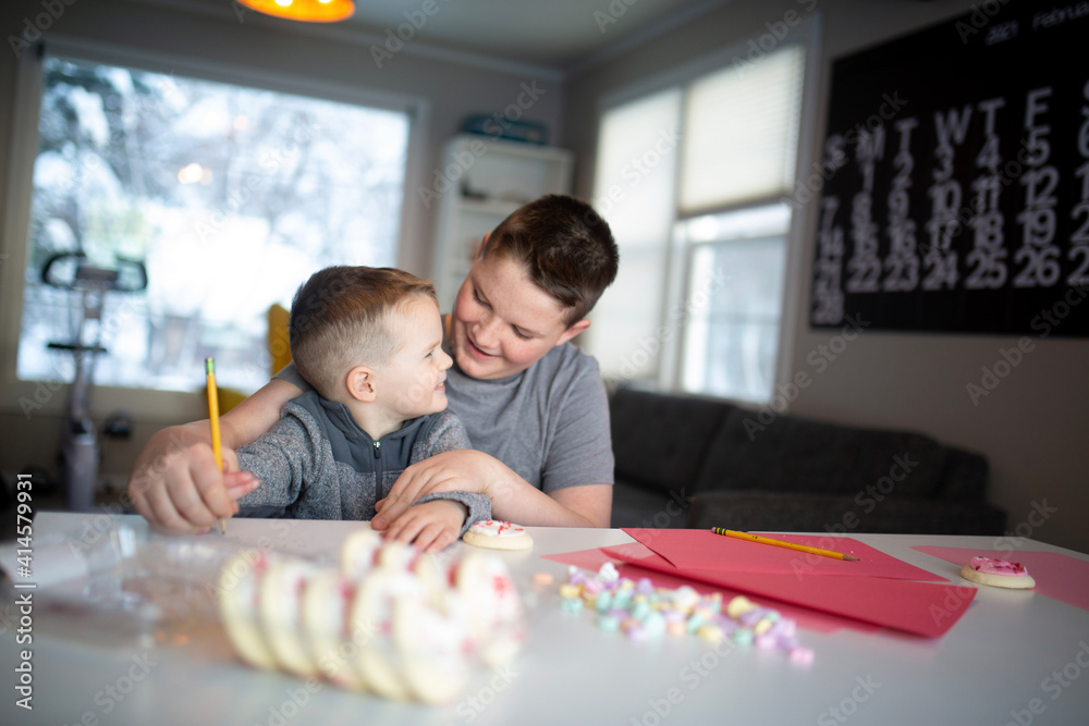 Fototapeta premium boy helping brother write valentine's day notes