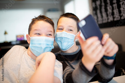 two boys in masks taking selfies