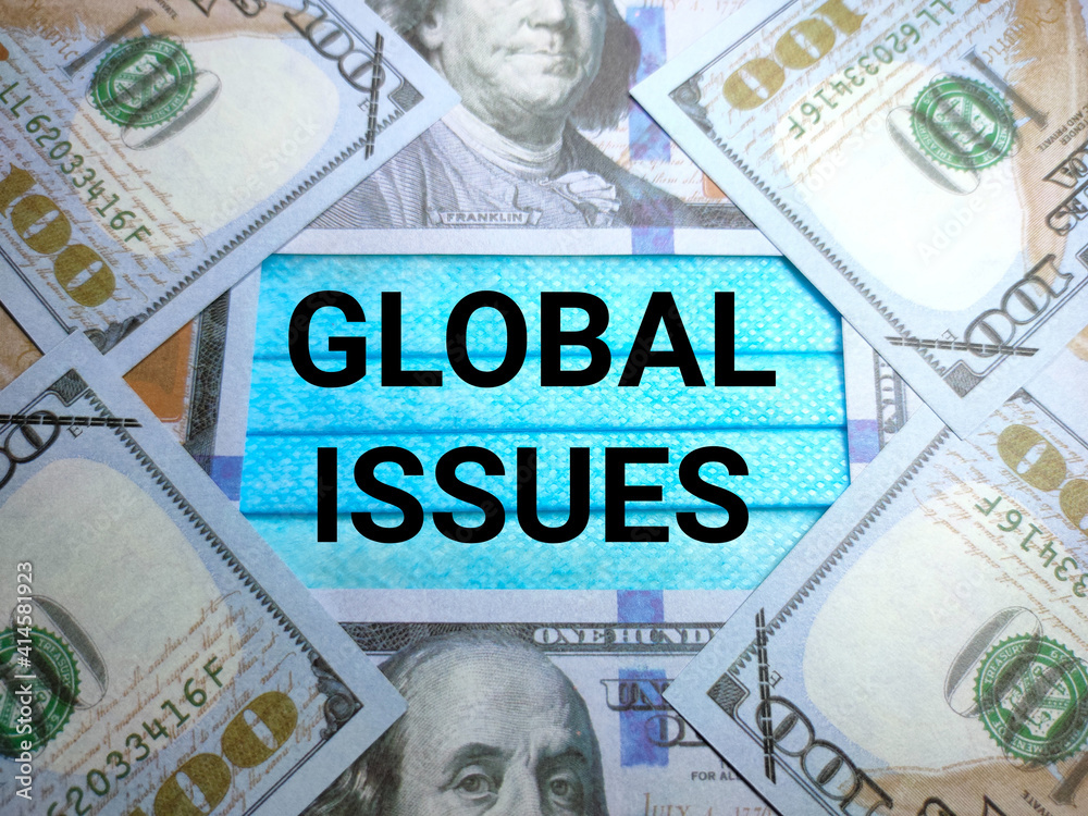 Fototapeta premium Selective focus of text GLOBAL ISSUES on a face mask with banknote.Shot were noise and grain.