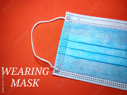 Selective focus of a word WEARING MASK with face mask on a red background.Shot were noise and grain.