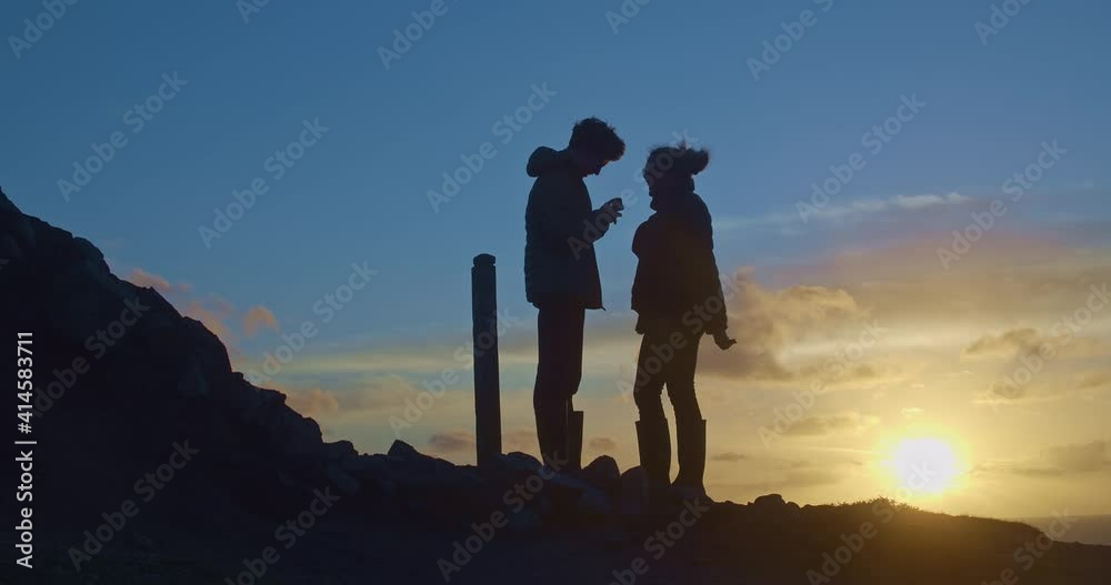 Silhouettes of man and woman against windy sunset on Cligga Head coastal hike Silhouettes of man and woman against windy sunset on Cligga Head coastal hike