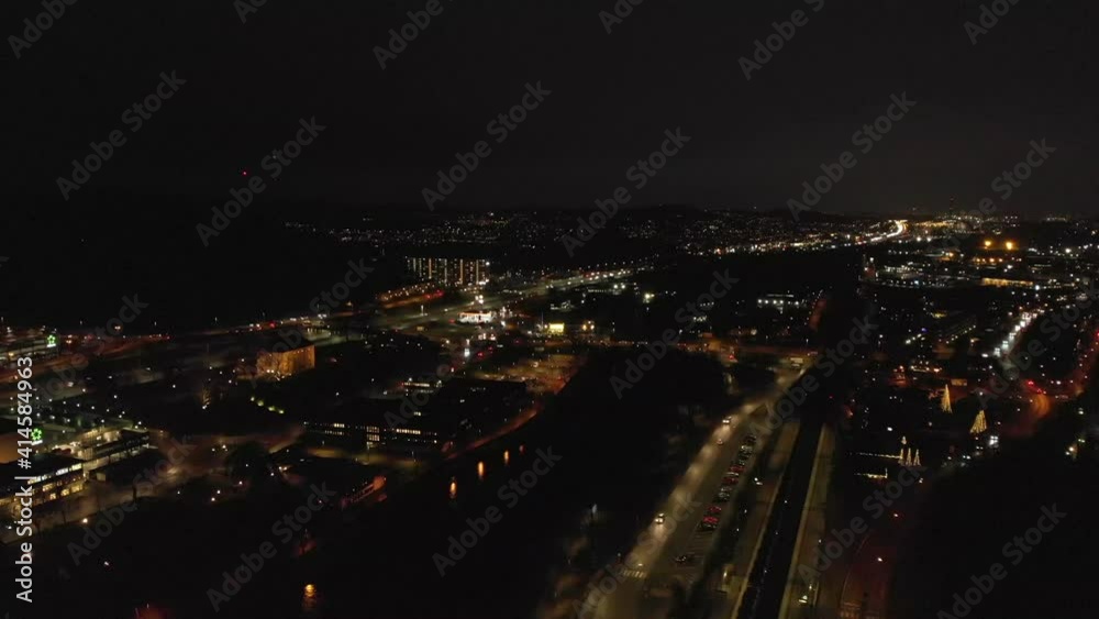 Stunning night-time aerial flying sideways above downtown Partille and European route E6 highway with illuminated skyline, buildings and street lights in Gothenburg City, Sweden. Stunning night-time aerial flying sideways above downtown Partille and European route E6 highway with illuminated skyline, buildings and street lights in Gothenburg City, Sweden.