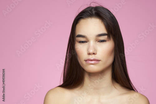 woman with bare shoulders clear skin body care pink background