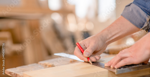 Close up man's hands taking measurement of a wooden plank. Empty space for text