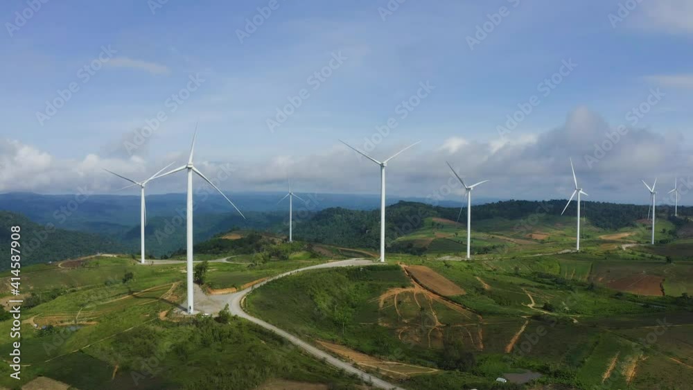 Aerial view of windmills rotating by the force of the wind for generating clean renewable energy for sustainable development in a green ecologic way on beautiful cloudy sky at highland. Aerial view of windmills rotating by the force of the wind for generating clean renewable energy for sustainable development in a green ecologic way on beautiful cloudy sky at highland.
