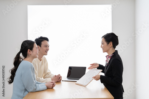 会話をするアジア人カップル夫婦と営業する女性 © ponta1414