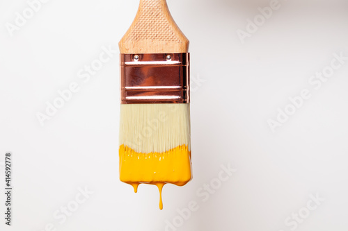 Fototapeta Naklejka Na Ścianę i Meble -  Close-up paintbrush with liquid yellow paint drips off the brush