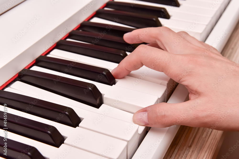 Obraz premium Woman's hands playing electronic digital piano at home. The woman is professional pianist arranging music using piano electronic keyboards. Musician practicing keyboard composing music