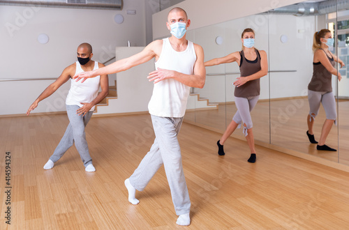 Portrait of man dancing during group workout in fitness center, all people wearing face masks and keeping social distance for viral protection