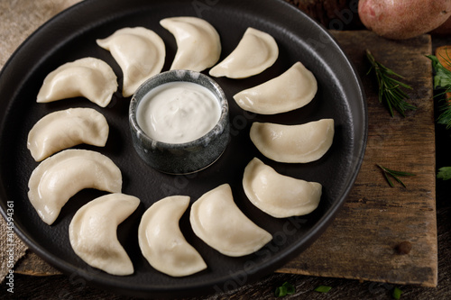 Appetizing traditional Russian dumplings, hand-made with potatoes. Still life on a wooden board. Close-up. photo