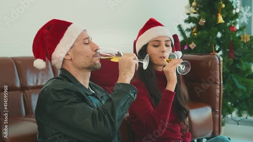 Man and woman couple in casual winter outfit sitting in living room drinking champagne and celebrate christmas event together with happy and romantic mood