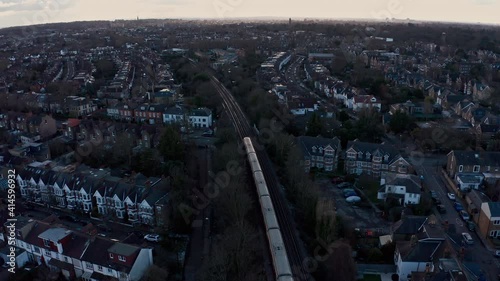 Cinematic follow drone shot of District line London underground train into Kew Railway photo