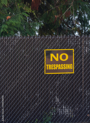 no trespassing warning sign on chain link wire fence