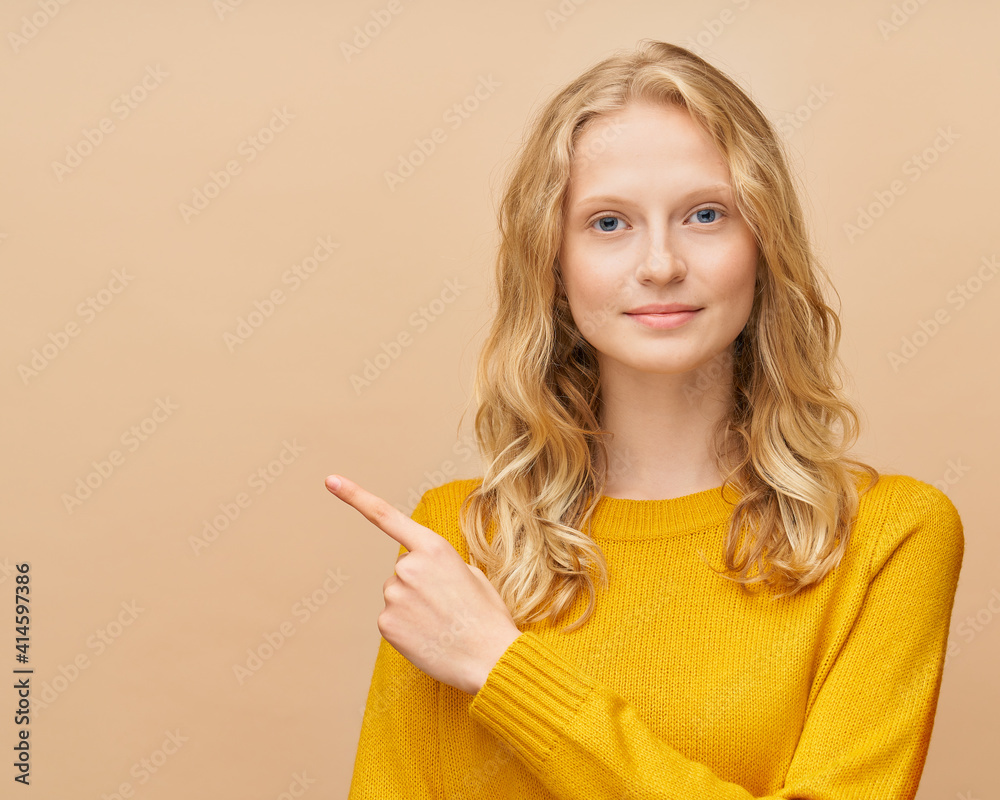 Waist up portrait of the woman pointing direction with finger, points with hand, beautiful young serious clever blonde Scandinavian female on bright yellow orange wall without makeup face Waist up portrait of the woman pointing direction with finger, points with hand, beautiful young serious clever blonde Scandinavian female on bright yellow orange wall without makeup face