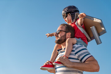 Father and son playing against blue summer sky background