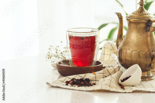 Composition with glass of tea and teapot on table