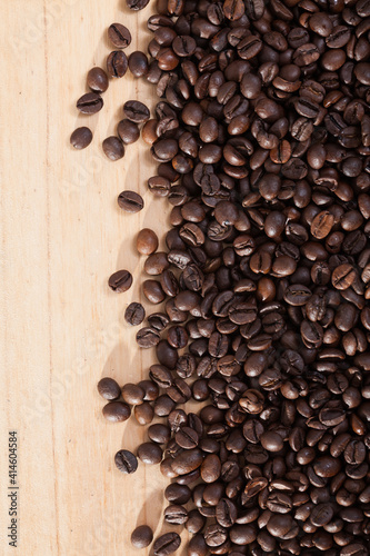 Picture of dark coffee beans on natural wooden background, no people
