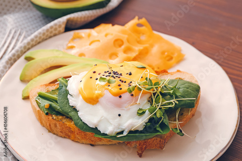 Fotografiet Tasty sandwich with florentine egg, avocado and cheese on wooden background, clo