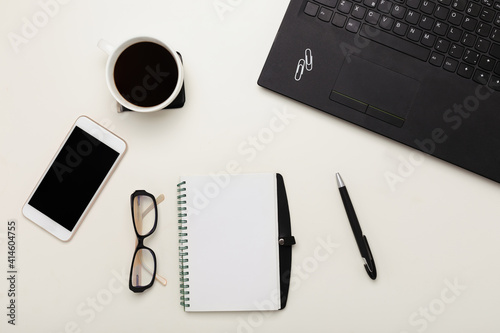 Obraz na płótnie workplace with black laptop, notepad, pen, glasses, a cup of coffee on a white t