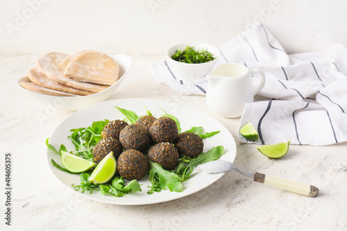 Plate with tasty falafel balls, arugula and lime on light background