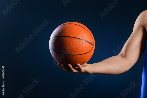 Hand of male basketball player with ball on dark background © Pixel-Shot