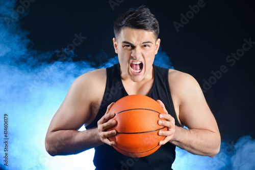 Aggressive male basketball player on dark background