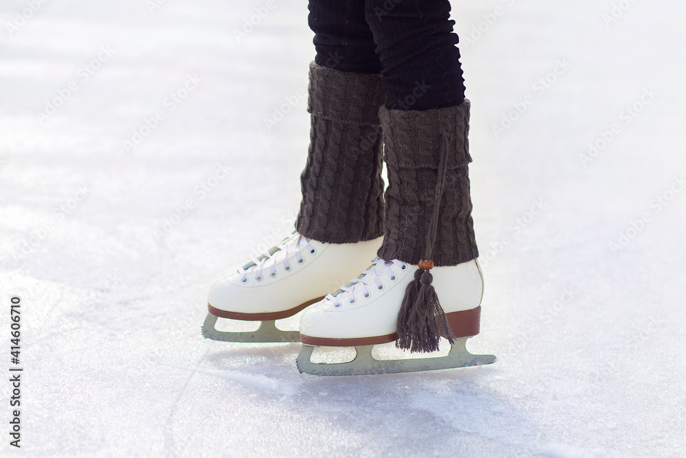 Legs in figure skates are on the ice on the rink. Classic white figure skates close-up. Legs in figure skates are on the ice on the rink. Classic white figure skates close-up.