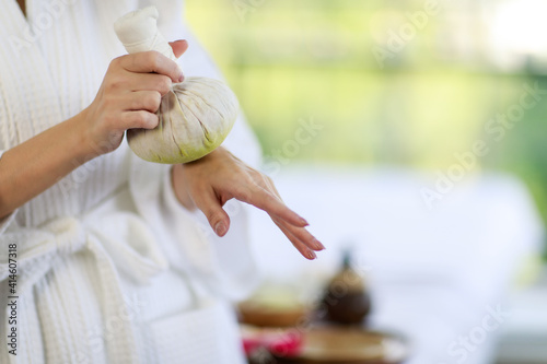Wallpaper Mural Focus to a right hand hold a herbal compress ball to left woman hand who is wearing a white robe, standing in the morning with blurred background Torontodigital.ca