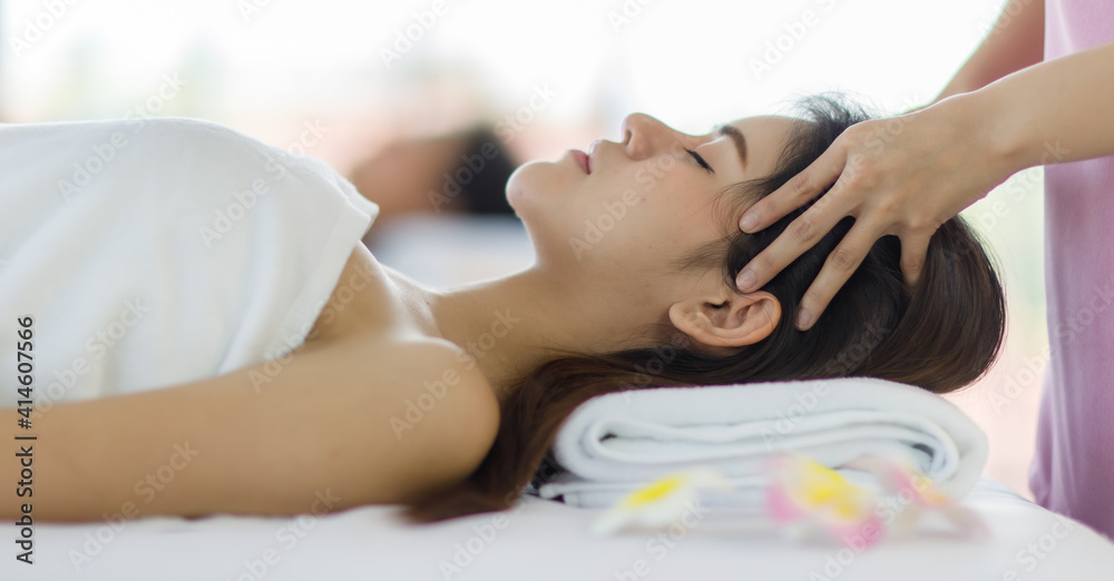 Adult beautiful asian women black long hair sleep for head massage spa service with covered wrap by white towel on her look feel relax and blurry with flowers background