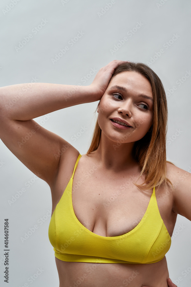 Portrait of lovely curvy young woman wearing yellow underwear looking aside, posing isolated over grey background Portrait of lovely curvy young woman wearing yellow underwear looking aside, posing isolated over grey background